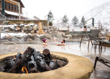 Fire pit with groups soaking in background at Iron Mountain Hot Springs CR Visit Glenwood Springs